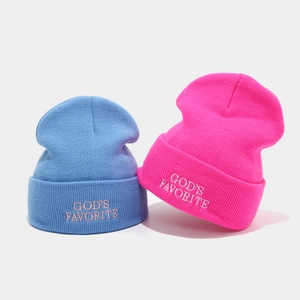 Gros plan de la broderie God's Favorite sur les bonnets en maille bleus et roses
