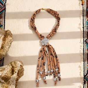 Détail d'un collier bohème tissé à glands avec fleur en strass et perles argentées