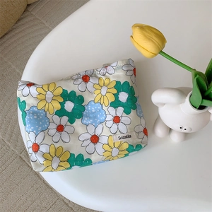 Close-up of small floral cotton makeup bag with daisy print on a minimalist white desk