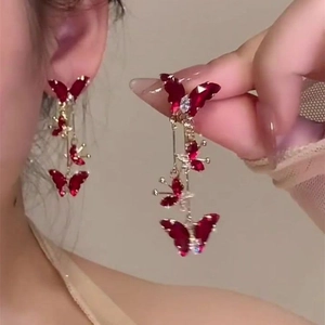 Long red butterfly tassel earrings with crystals and pearl accents on elegant model