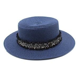 Detailed texture of navy blue boater straw hat with tweed band and golden M logo