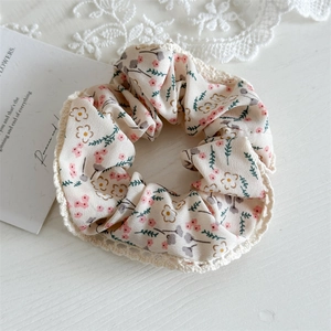 Detailed view of floral hair scrunchie with pink blossoms and white lace trim edge