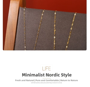Detail of four thin golden necklaces displayed on dark grey velvet jewelry stand