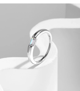 Detailed view of an emerald cut cubic zirconia ring on a minimalist white stone pedestal