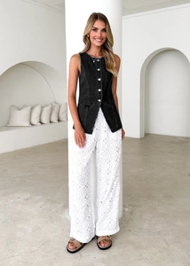 Detail of a black denim sleeveless vest paired with white lace hollow-out wide-leg pants