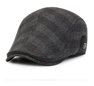 Close-up of winter flat cap showing grey plaid fabric and metal side buckle detail