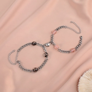 Matching couple bracelets with heart magnets and beads on elegant pink silk background