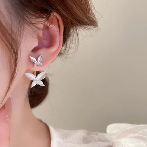 Close-up of a double-layered white butterfly earring on model showing elegant gold trim