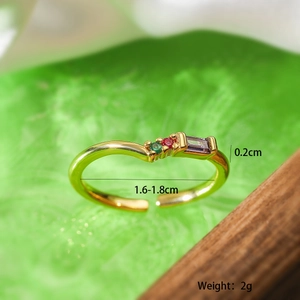 Macro shot of gold-plated wave ring with green, red, and purple zircon gemstones