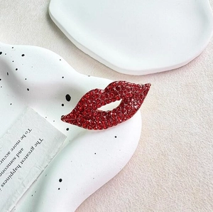 Sparkling red lip brooch with pavé rhinestones on a white ceramic display plate