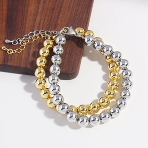 Polished gold and silver hollow bead bracelets with lobster clasp on a wooden base