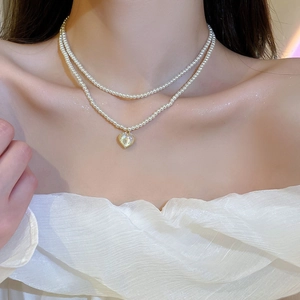 Double-layer pearl necklace with heart pendant shown on model neck and collarbone