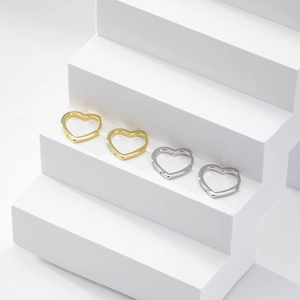 Minimalist heart-shaped hoop earrings in gold and silver finish on white background