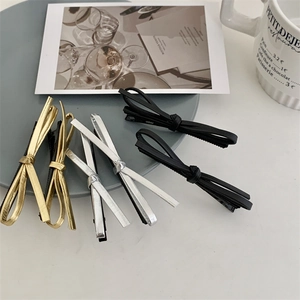 Close-up of black leather bow hair clips with metallic details on a modern tray