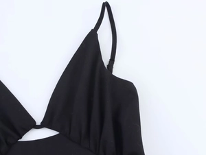 Dettaglio dello scollo e delle sottili spalline della mini abito nero su sfondo bianco