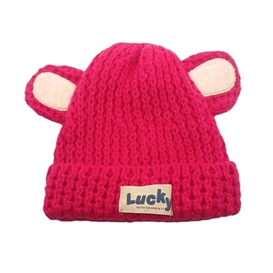 Détail d'un bonnet en maille rose avec oreilles d'ours et étiquette Lucky sur fond blanc