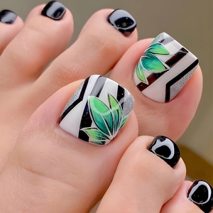 Detail of toe nail tips with black stripes, green leaf patterns, and silver glitter