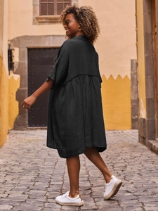 Street style view of dark grey loose cotton linen midi dress on a cobblestone street