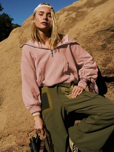 Close-up of pink half-zip hoodie featuring drop shoulders and a large front pocket