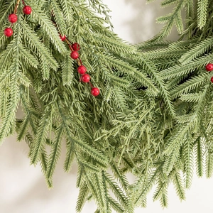 Christmas wreath with green pine needles and red berries on a neutral background