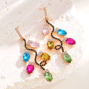 Détail de boucles d'oreilles lianes avec cristaux colorés taille poire sur pierre blanche