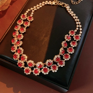 Close-up of luxury gold-plated necklace with sparkling red rhinestones and floral layered design