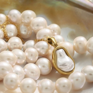 Macro shot of irregular white baroque pearl pendant on thin gold chain necklace