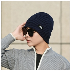 Close-up of deep blue knitted beanie with FARD label and cozy winter fabric texture