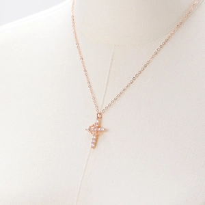 Detailed view of rose gold crown cross necklace with zircons on a neck mannequin