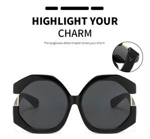 Detail view of large cat-eye sunglasses featuring golden hinges and gray lenses