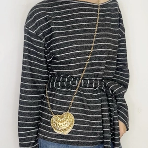 Detail of heart-shaped woven mini crossbody bag in gold finish with metal chain