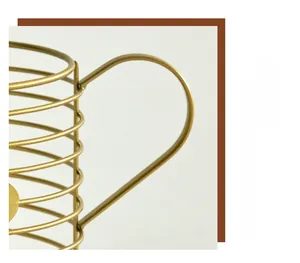 Detail showing the curved gold metal handle of the iron coffee pod storage basket