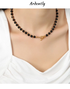 Detail of black onyx bead necklace with a golden OT toggle clasp on a model neck