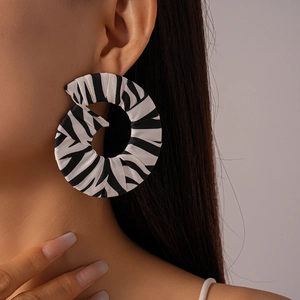 Gros plan sur des boucles d'oreilles créoles en tissu zèbre avec plis en spirale