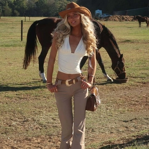 Dettaglio di un top bianco con scollo a V profondo abbinato ad accessori in stile western