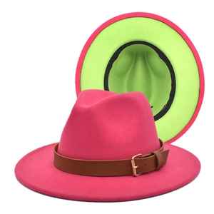 Detail of wide brim fedora hat in rose red and neon green with brown leather belt buckle