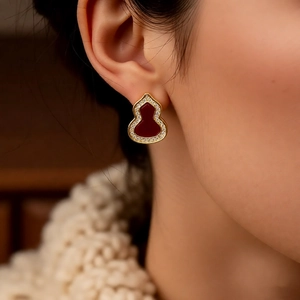 Macro shot of a red Wulu gourd stud earring with white crystal pave on a female model