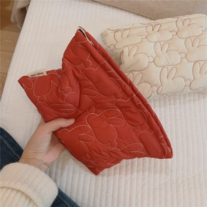 Close-up of red quilted pouch with cute rabbit patterns and simple wish label