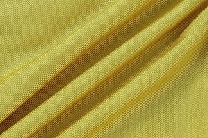 Macro view of textured mustard yellow ribbed knit fabric for elegant summer dresses