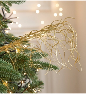 Detail of glittery gold curled branches for Christmas tree decor with warm bokeh lights