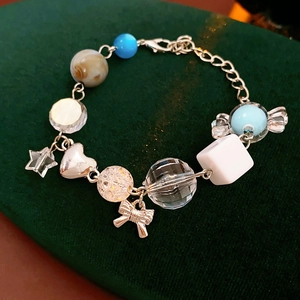 Detailed macro view of beaded bracelet with star and bow charms on green velvet