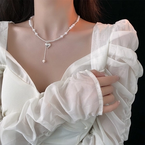 Elegant heart pendant necklace with pearl fringe detail shown on a model neck