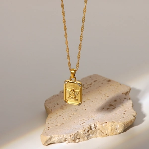Detailed view of 18K gold plated square pendant featuring angel relief and inset crystals