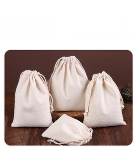 Detailed view of four sizes of drawstring cotton canvas storage bags on wooden surface