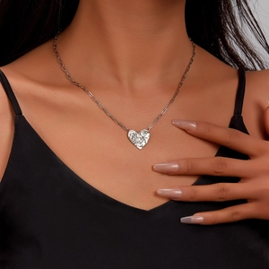 Polished silver heart pendant necklace with textured surface worn on a female model