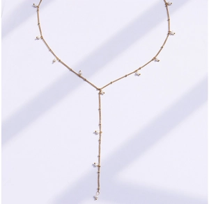 Detailed close-up of a minimalist 18K gold Y-shaped lariat necklace with white pearls