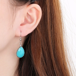 Détail de boucles d'oreilles goutte avec pierres facettées bleues sur un mannequin