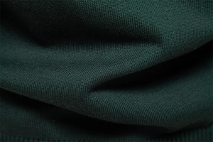 Macro shot of dark green knit fabric texture with premium stitching details