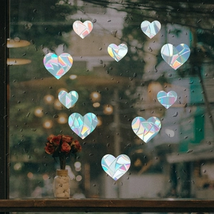 Rainbow prism heart-shaped holographic window stickers on rain-covered glass surface