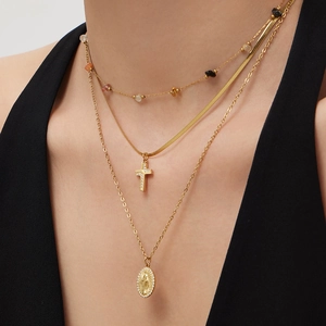 Three-layer gold necklace set with cross pendant, oval medallion, and colorful stones